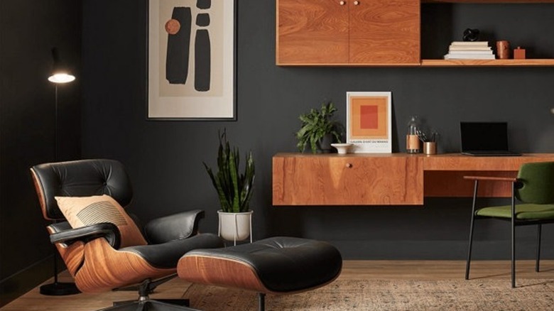 A desk area painted dark gray with comfortable chairs and plants
