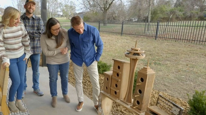 Jenny and Dave Marrs show their Seattle-themed birdhouses to a couple in their yard.