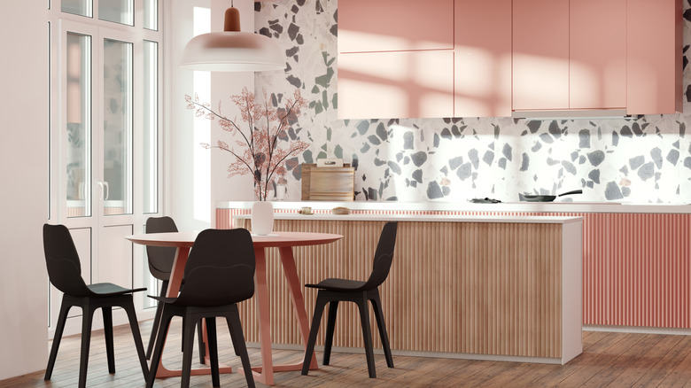 A kitchen with blush pink cabinets and a terrazzo backsplash