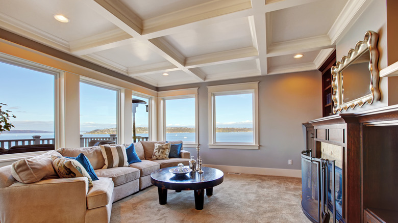 Warm living room with coffered ceiling and a sofa, fireplace and coffee table.