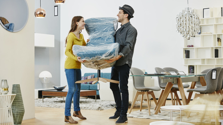 A woman and a man carrying a new chair.
