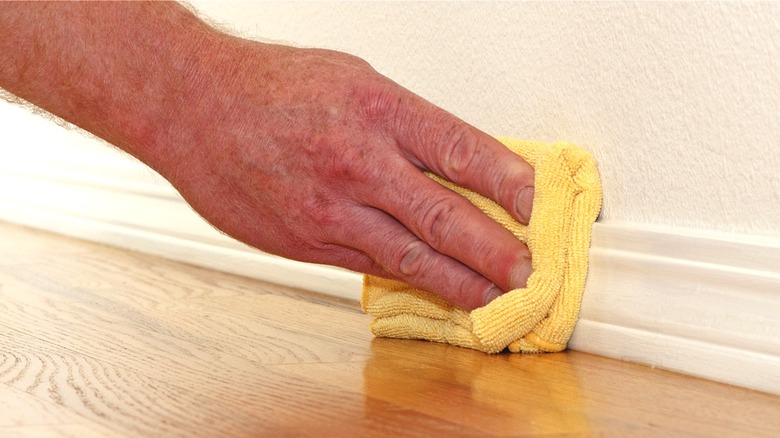 Hand cleaning baseboards with cloth