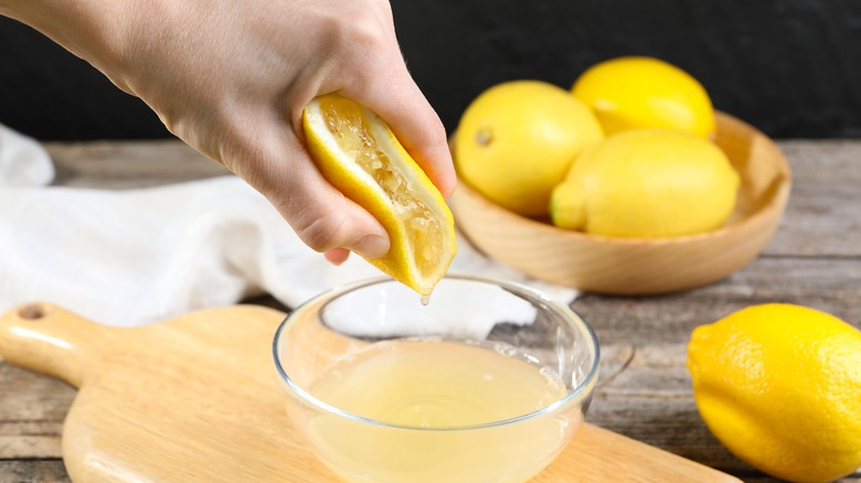 Hand squeezing a lemon into a bowl