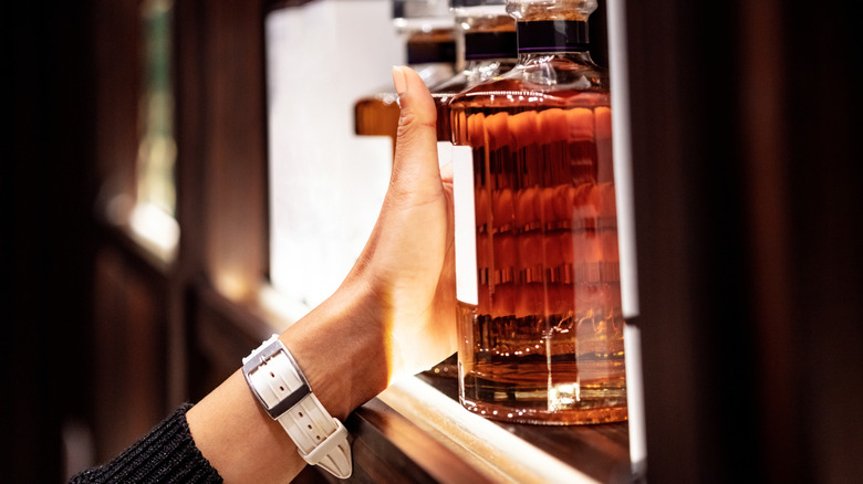 Woman puts a bottle of whiskey on a shelf