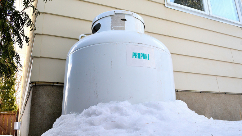 A propane tank half buried in snow