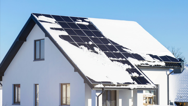 Solar panels on a house roof partially covered in snow