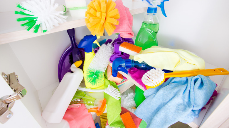 Cleaning supplies cluttered under the cabinet.