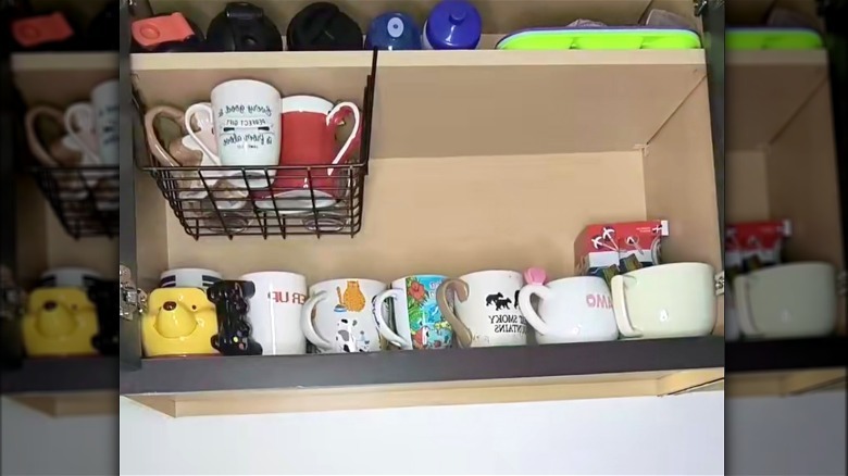 Slide on storage basket holding coffee mugs in a cupboard