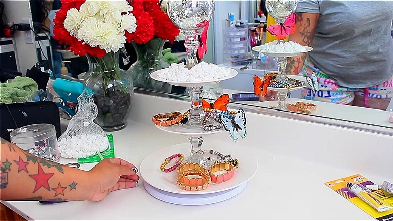 Hand holding a tiered jewelry organizer on a white countertop