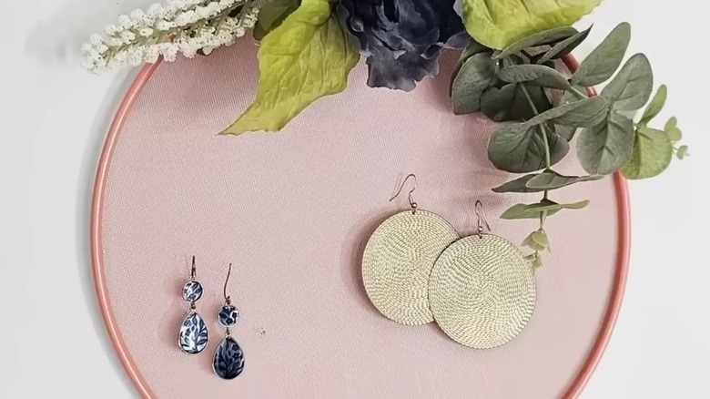 A decorated mesh strainer holding two pairs of earrings