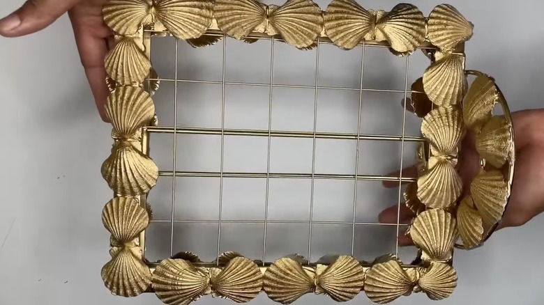 Hands holding a golden wire earring organizer