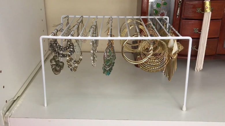 Earrings hanging on a white wire shelf