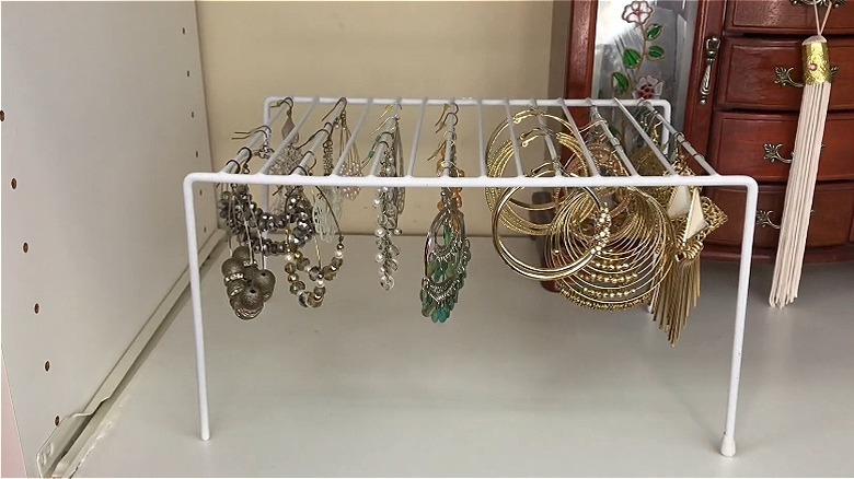 Earrings hanging on a white wire shelf