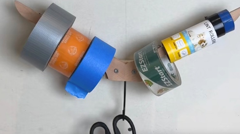 mounted upside-down wooden clothes hanger storing tape rolls and scissors in garage