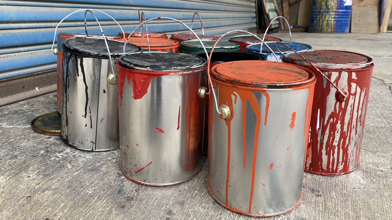 A collection of old paint cans sits on a garage floor