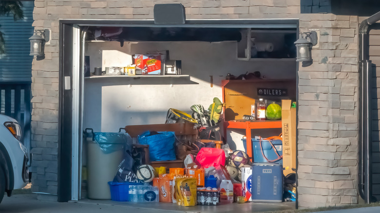 The door of a messy garage is wide open