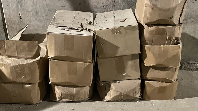 Dusty cardboard boxes sit in a pile on a concrete floor