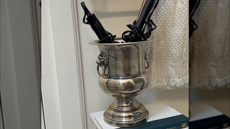 A metal ice bucket holding hair tools.