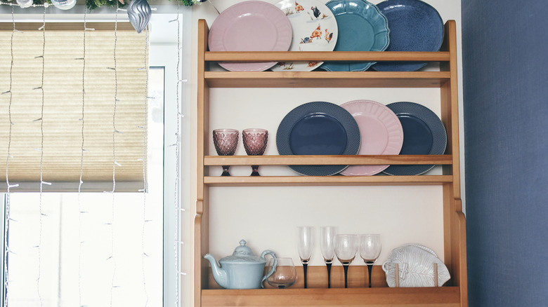 Wooden plate rack with fancy plates and glasses.