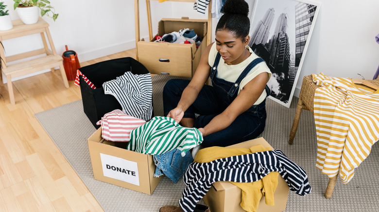 Woman decluttering her clothes and putting them in boxes