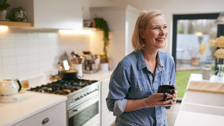 Older woman in kitchen holding a mug