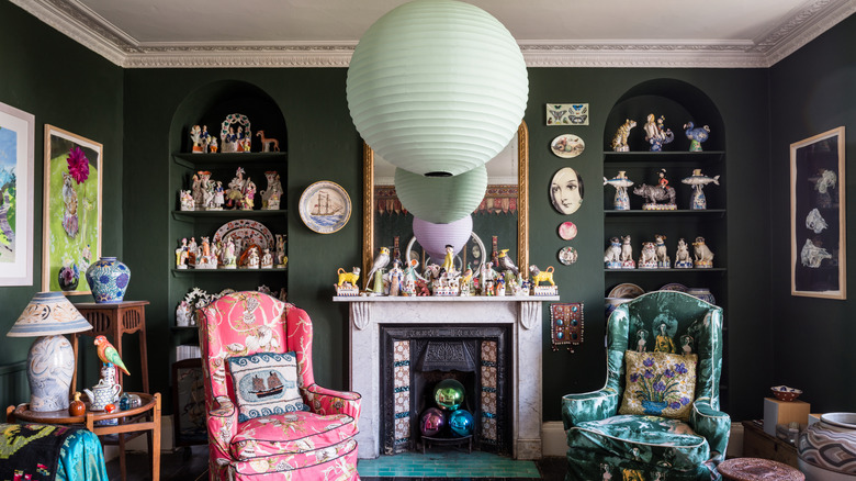 Maximalist living room with trinkets displayed on shelves and above the fireplace
