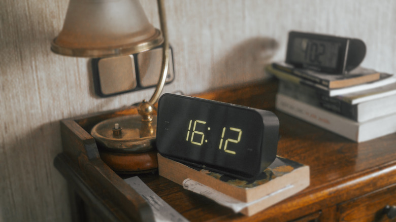 Cluttered bedside table with digital alarm clocks