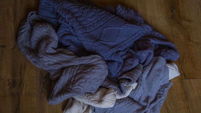 A pile of sweaters on the floor getting wrinkled