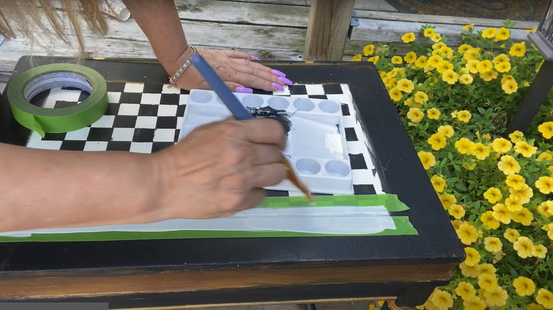 A person painting a checkered design onto a table