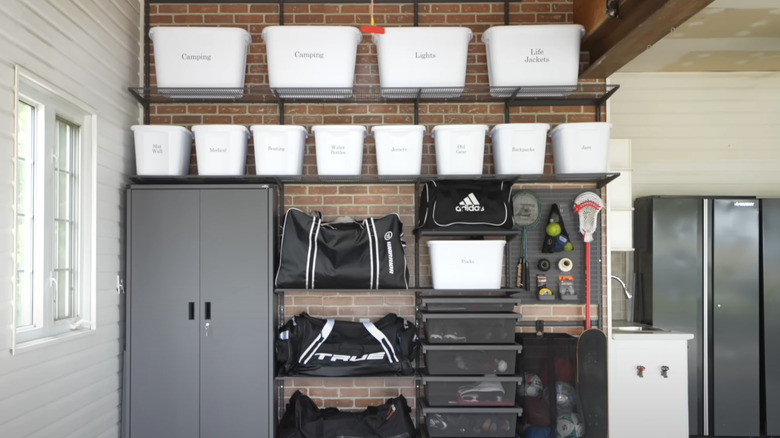 White plastic bins with clear labels on shelves keep this garage tidy