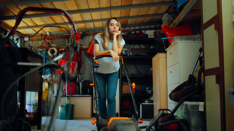 Woman stands in her cluttered garage, trying to think of a way to declutter it.