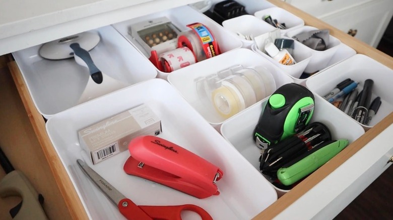 An organized junk drawer with white bins