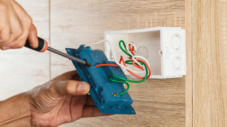 Electrician installing an outlet box inside a cabinet