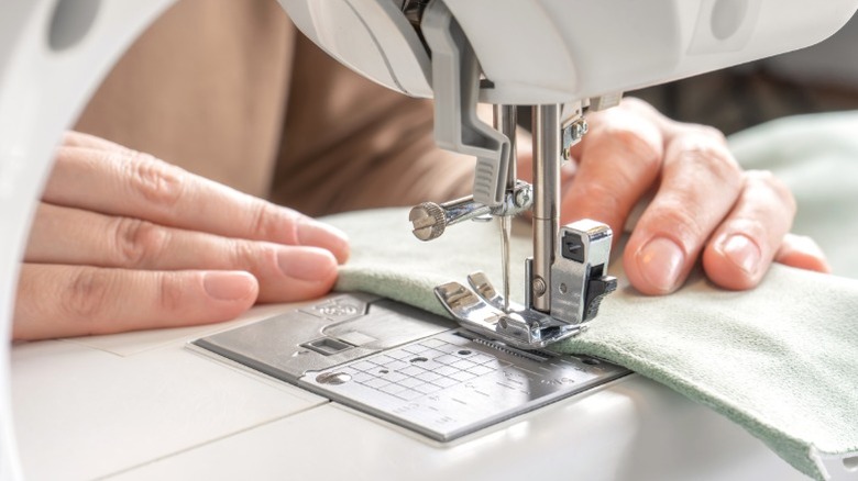 Person hemming edge of fabric with sewing machine to make cloth lid holder