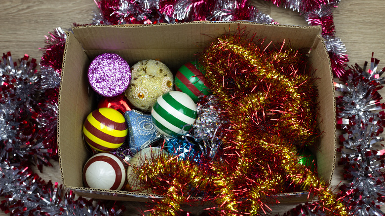 A cardboard box full of tinsel and ornaments