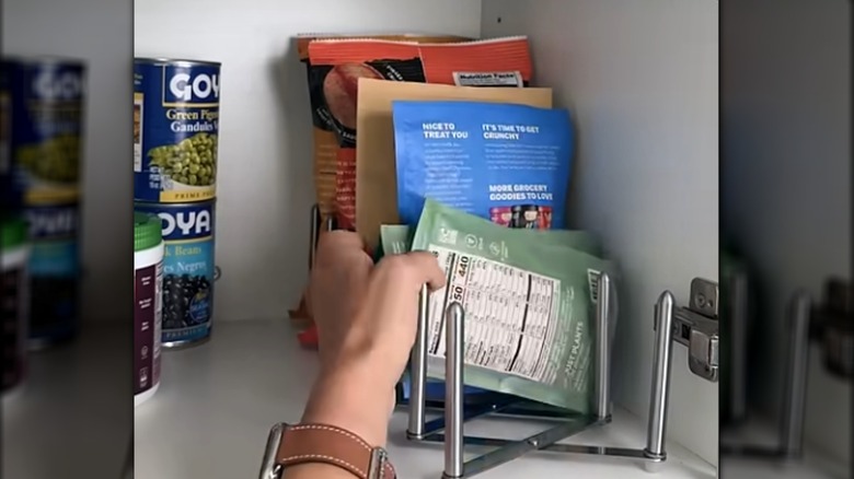 Hand putting snack bags in IKEA pot lid organizer