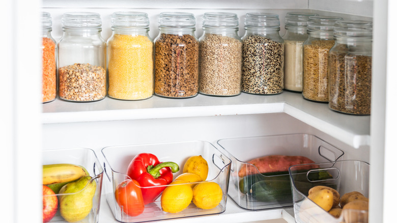 A pantry organized with clear containers holding various produce and staple products.