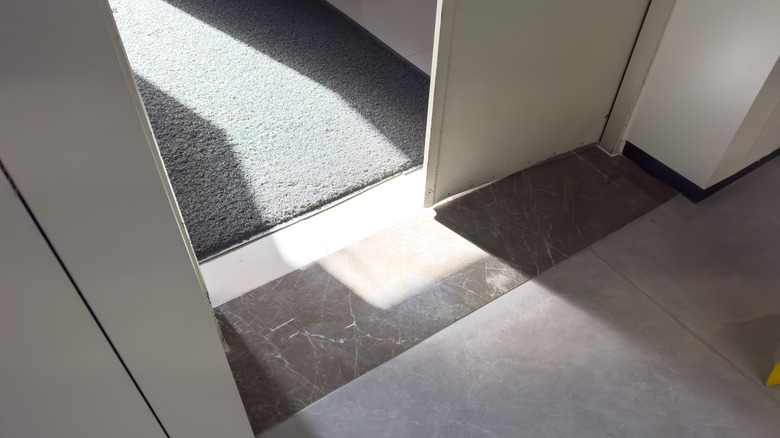 Carpet in a doorway leading to stone tiles