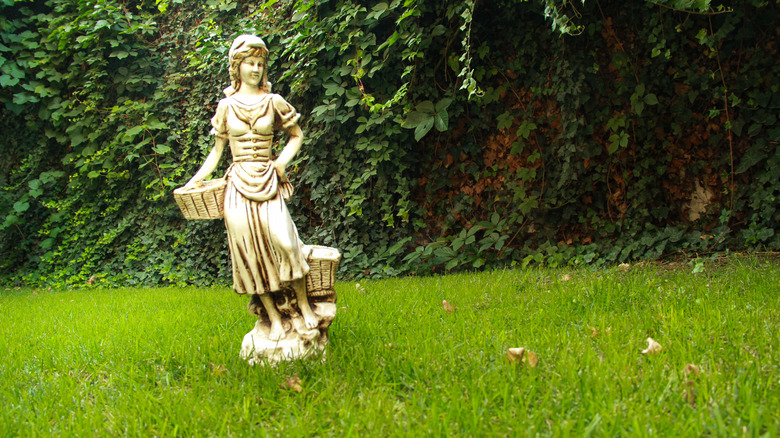 A statue of a girl holding baskets in a lawn