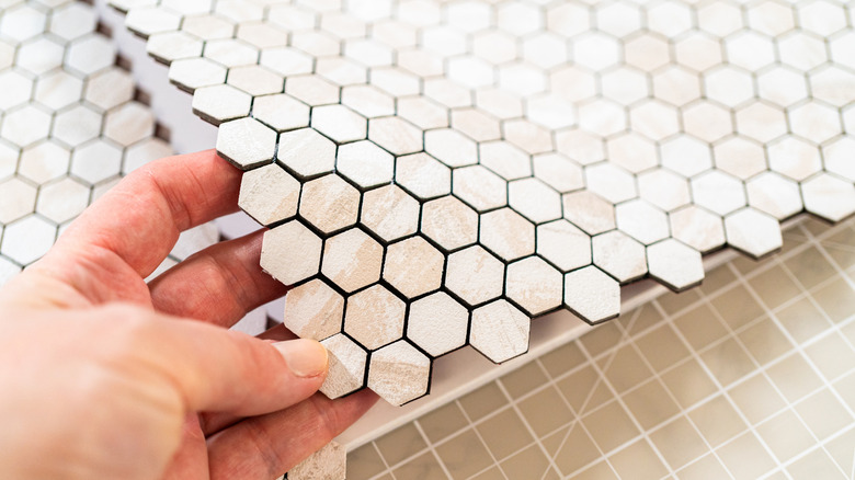 Hand laying down a peel and stick tile on a surface
