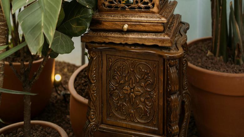 An ornate vintage phonograph sits among tropical leaves