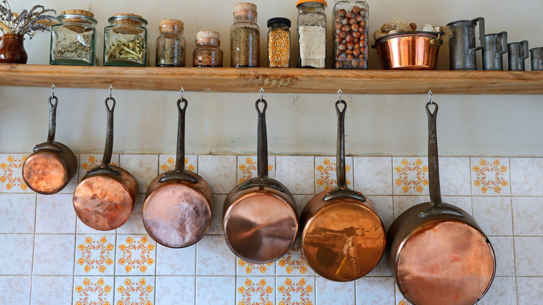 A shelf displaying vintage items with copper pans hanging below