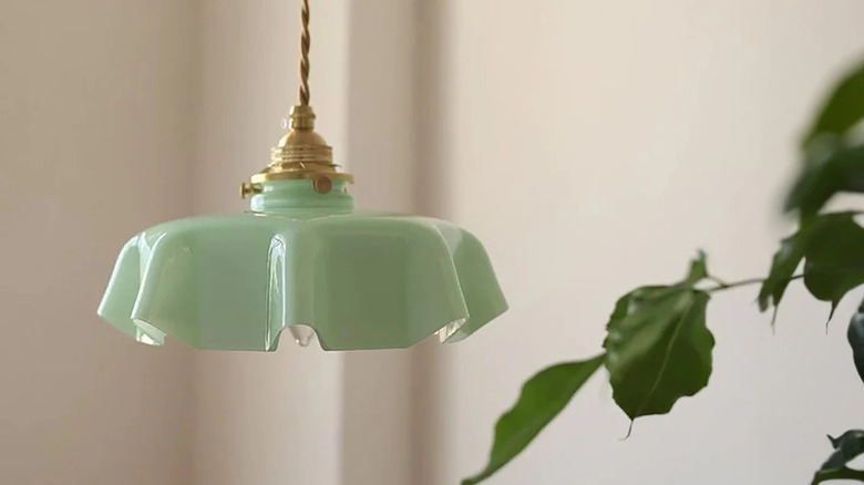 A Jade Glass pendant light hangs from the ceiling next to a leafy plant