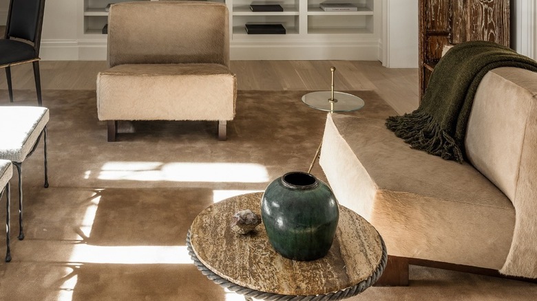A verdant urn and olive green throw blanket accent a neutral living room in The Katherine at 118 West 13