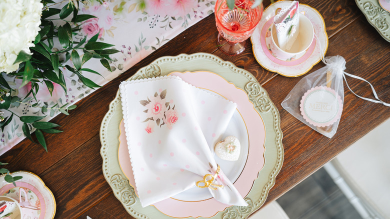 Mixed dishware in spring colors, including green dinner plate, pink appetizer plate, and pink-tinted drinking glass