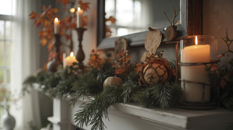A mantel decorated for flal with candles and greenery