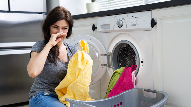 woman covers nose beside washer