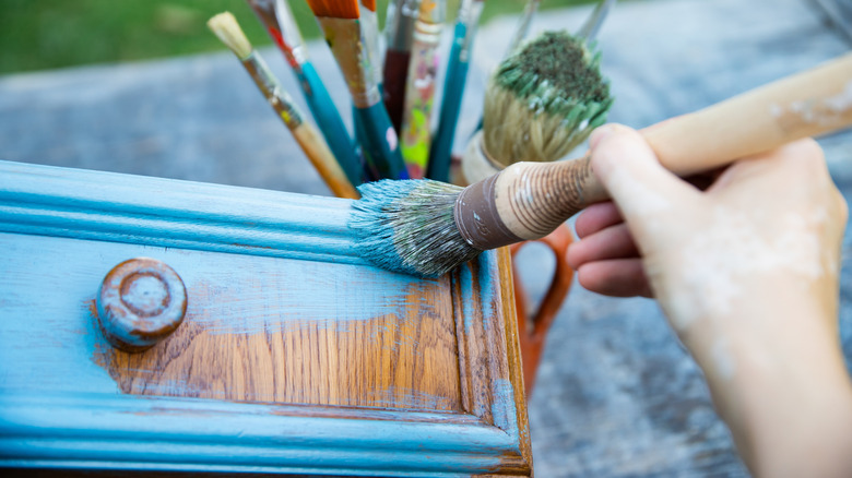 Person painting wooden furniture blue