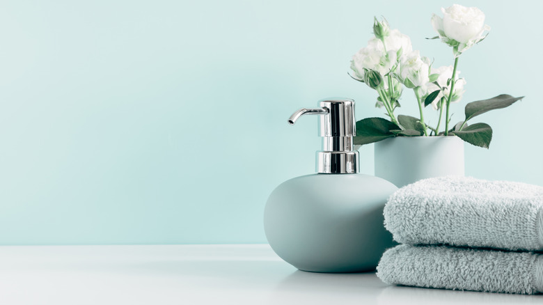 Aqua towels beside soap dispenser and flowers