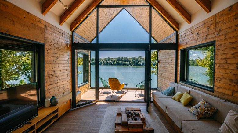 Living room with drenched wood walls and beams overlooking a lake